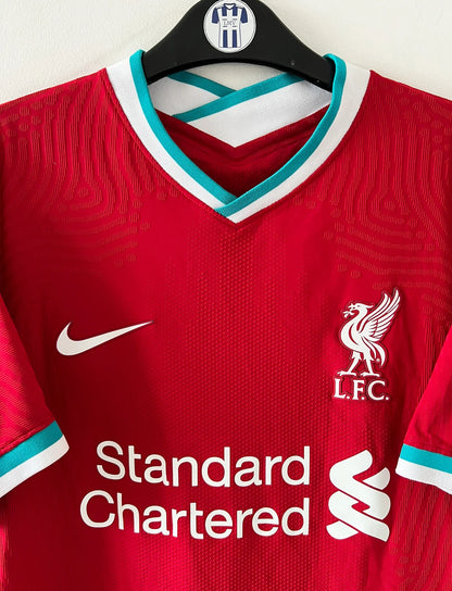 Maillot de foot vintage domicile rouge de Liverpool 2020/2021 en version vapor. On peut retrouver l'équipementier Nike et le sponsor Standard Chartered. Il s'agit d'un maillot authentique d'époque.