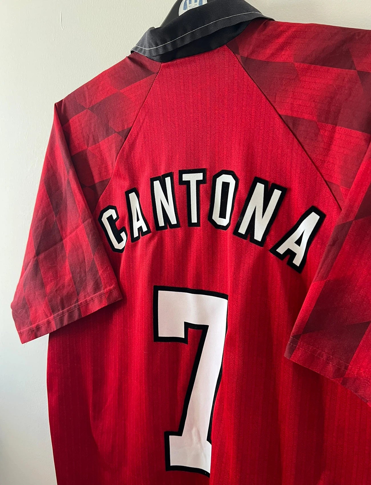Maillot de foot vintage domicile rouge de Manchester United 1996/1998. On peut retrouver l'équipementier Umbro et le sponsor Sharp. Le maillot est floqué du numéro 7 Eric Cantona. Il s'agit d'un maillot authentique d'époque.