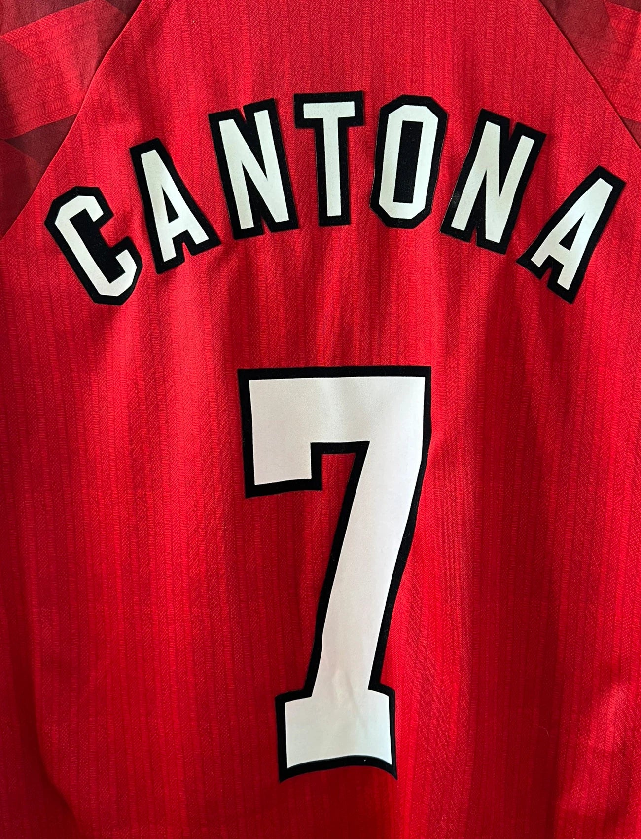 Maillot de foot vintage domicile rouge de Manchester United 1996/1998. On peut retrouver l'équipementier Umbro et le sponsor Sharp. Le maillot est floqué du numéro 7 Eric Cantona. Il s'agit d'un maillot authentique d'époque.