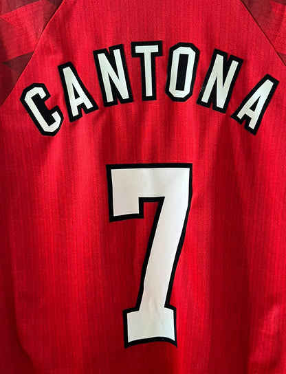 Maillot de foot vintage domicile rouge de Manchester United 1996/1998. On peut retrouver l'équipementier Umbro et le sponsor Sharp. Le maillot est floqué du numéro 7 Eric Cantona. Il s'agit d'un maillot authentique d'époque.