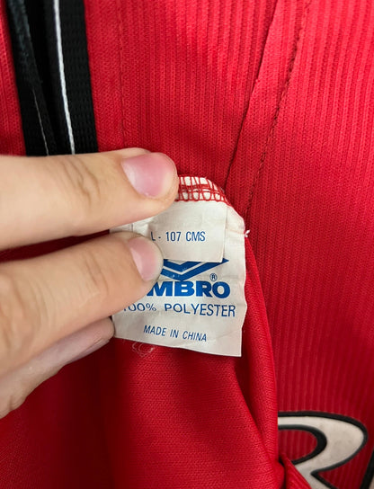 Maillot de foot vintage domicile rouge de Manchester United saison 1998/2000. On peut retrouver l'équipementier Umbro et le sponsor Sharp. Il s'agit d'un maillot authentique d'époque.