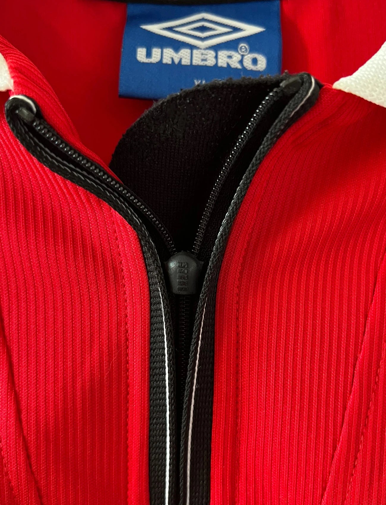 Maillot de foot vintage domicile rouge de Manchester United saison 1998/2000. On peut retrouver l'équipementier Umbro et le sponsor Sharp. Il s'agit d'un maillot authentique d'époque.