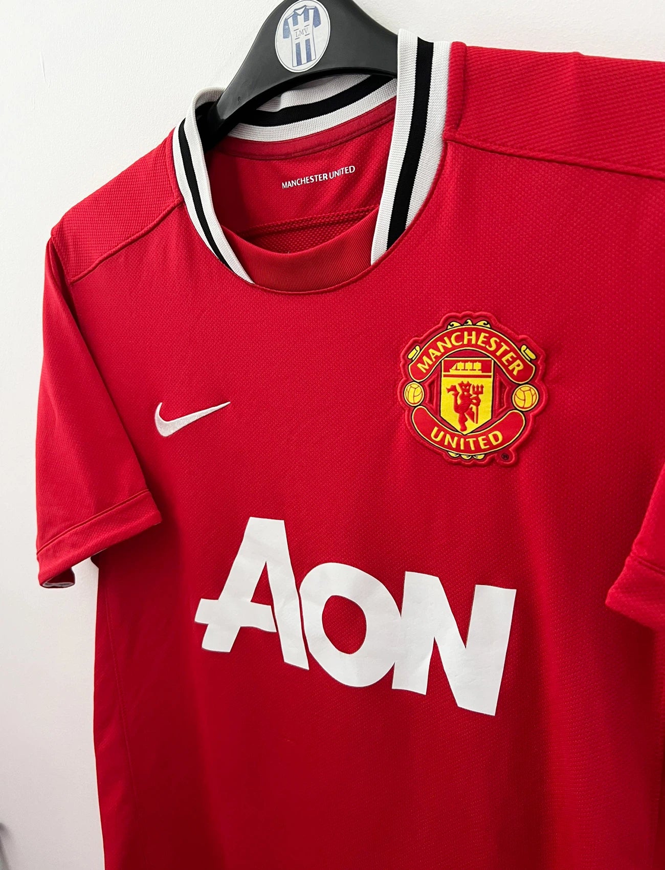 Maillot de foot vintage domicile rouge de Manchester United 2011/2012. On peut retrouver l'équipementier Nike et le sponsor Aon. Il s'agit d'un maillot authentique d'époque.