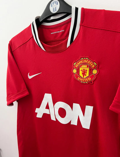Maillot de foot vintage domicile rouge de Manchester United 2011/2012. On peut retrouver l'équipementier Nike et le sponsor Aon. Il s'agit d'un maillot authentique d'époque.