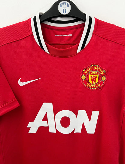 Maillot de foot vintage domicile rouge de Manchester United 2011/2012. On peut retrouver l'équipementier Nike et le sponsor Aon. Il s'agit d'un maillot authentique d'époque.