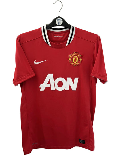 Maillot de foot vintage domicile rouge de Manchester United 2011/2012. On peut retrouver l'équipementier Nike et le sponsor Aon. Il s'agit d'un maillot authentique d'époque.