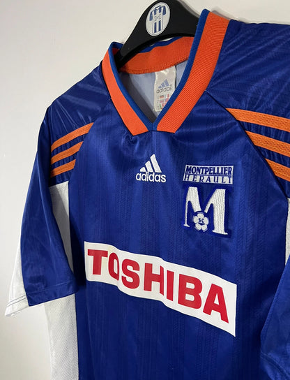 Maillot de foot vintage domicile bleu de Montpellier de la saison 1999/2000. On peut retrouver l'équipementier Adidas et le sponsor Toshiba. Il s'agit d'un maillot authentique d'époque.