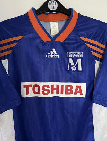 Maillot de foot vintage domicile bleu de Montpellier de la saison 1999/2000. On peut retrouver l'équipementier Adidas et le sponsor Toshiba. Il s'agit d'un maillot authentique d'époque.