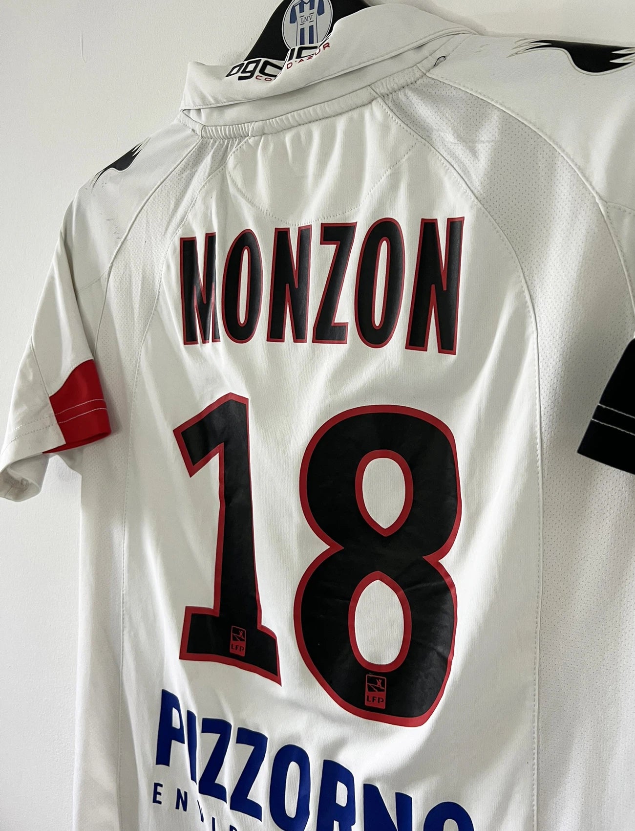 Maillot de foot vintage extérieur blanc de l'OGC Nice porté par Fabian Monzon lors de la saison 2011/2012. On peut retrouver l'équipementier Burrda Sport et le sponsor Mutuelle du Soleil. Le maillot est floqué du numéro 18 Fabian Monzon. Il s'agit d'un maillot authentique d'époque.