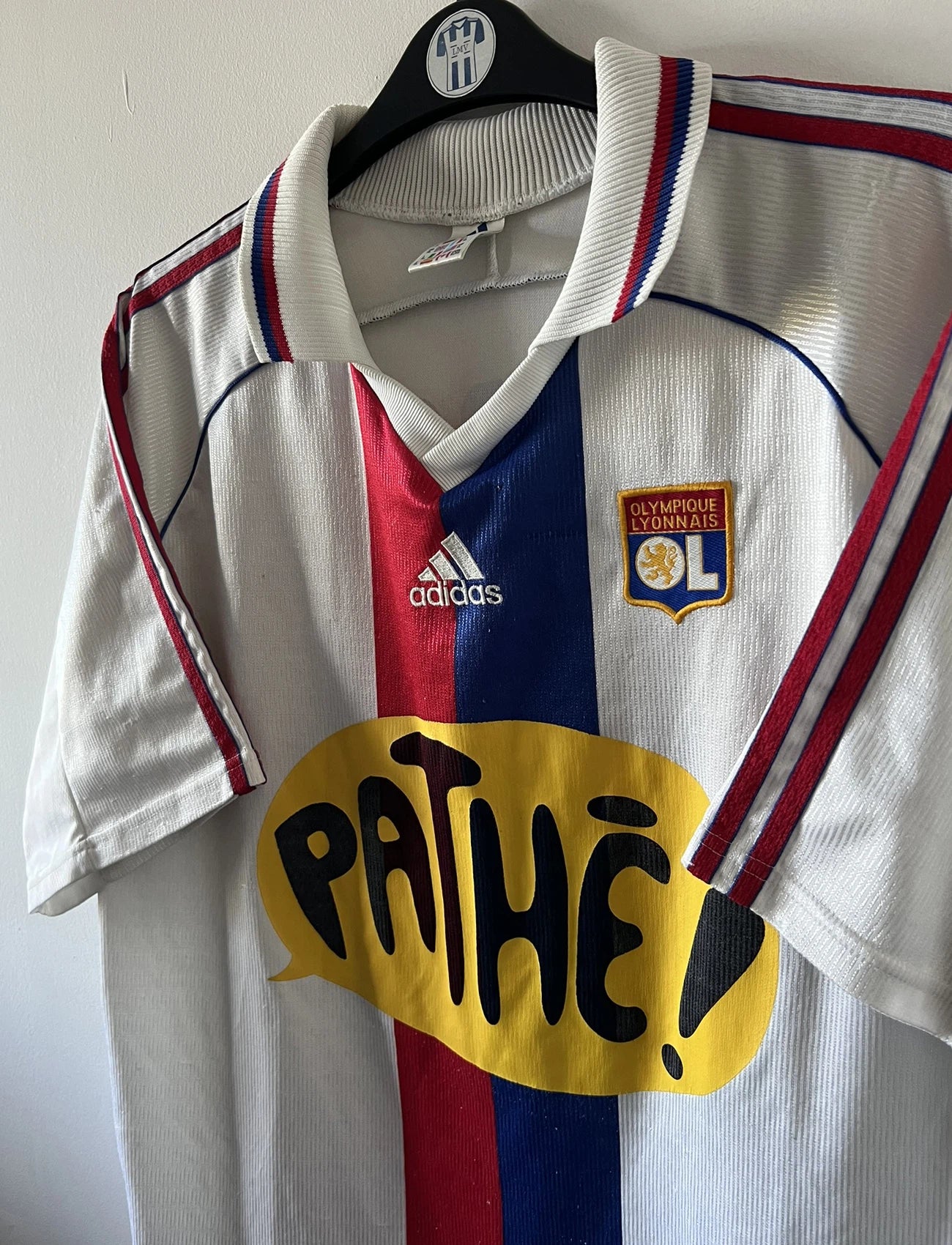 Maillot de foot vintage domicile blanc de l'OL 1999/2000. On peut retrouver l'équipementier Adidas et le sponsor Pathé. Le maillot est floqué du numéro 9 Sonny Anderson. Il s'agit d'un maillot authentique d'époque