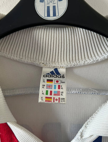 Maillot de foot vintage domicile blanc de l'OL 1999/2000. On peut retrouver l'équipementier Adidas et le sponsor Pathé. Le maillot est floqué du numéro 9 Sonny Anderson. Il s'agit d'un maillot authentique d'époque