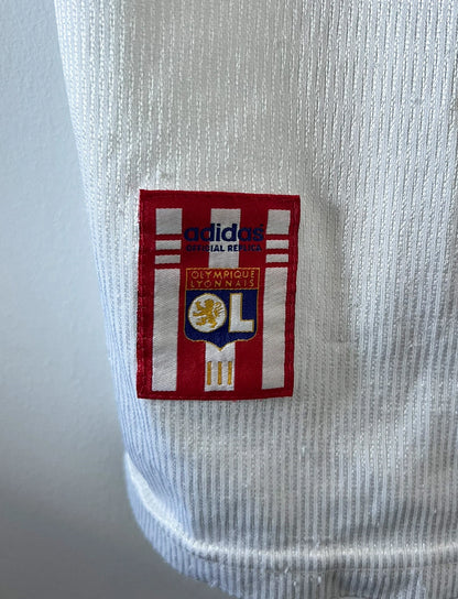 Maillot de foot vintage domicile blanc de l'OL 1999/2000. On peut retrouver l'équipementier Adidas et le sponsor Pathé. Le maillot est floqué du numéro 9 Sonny Anderson. Il s'agit d'un maillot authentique d'époque