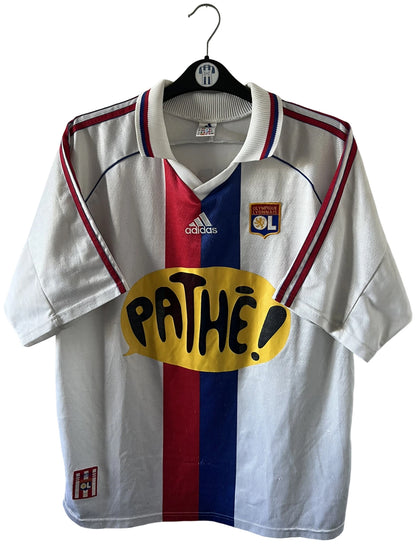 Maillot de foot vintage domicile blanc de l'OL 1999/2000. On peut retrouver l'équipementier Adidas et le sponsor Pathé. Le maillot est floqué du numéro 9 Sonny Anderson. Il s'agit d'un maillot authentique d'époque