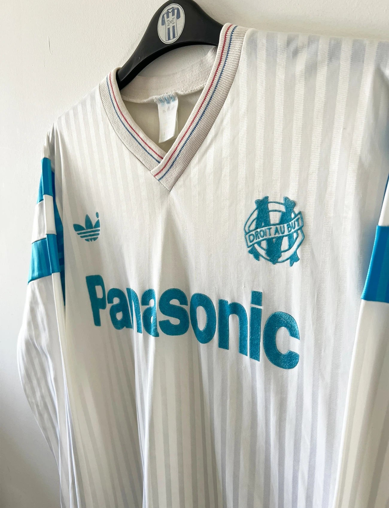 Maillot de foot vintage domicile blanc de l'OM 1989/1991. On peut retrouver l'équipementier Adidas et le sponsor Panasonic. Il s'agit d'un maillot authentique d'époque.