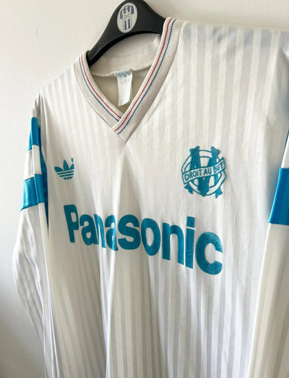 Maillot de foot vintage domicile blanc de l'OM 1989/1991. On peut retrouver l'équipementier Adidas et le sponsor Panasonic. Il s'agit d'un maillot authentique d'époque.
