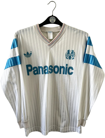 Maillot de foot vintage domicile blanc de l'OM 1989/1991. On peut retrouver l'équipementier Adidas et le sponsor Panasonic. Il s'agit d'un maillot authentique d'époque.