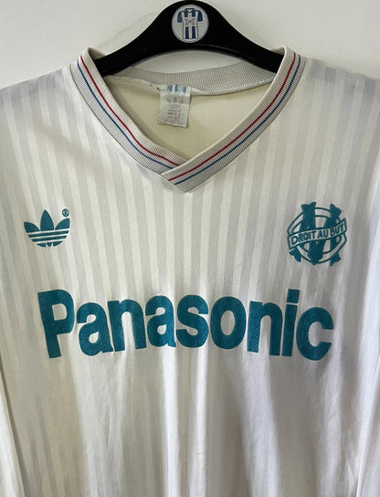 Maillot de foot vintage domicile blanc de l'OM 1989/1991. On peut retrouver l'équipementier Adidas et le sponsor Panasonic. Il s'agit d'un maillot authentique d'époque.