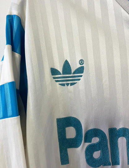 Maillot de foot vintage domicile blanc de l'OM 1989/1991. On peut retrouver l'équipementier Adidas et le sponsor Panasonic. Il s'agit d'un maillot authentique d'époque.