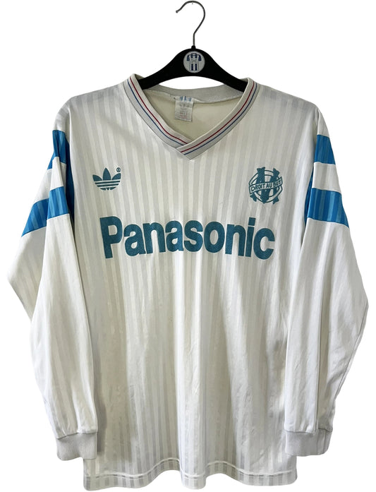 Maillot de foot vintage domicile blanc de l'OM 1989/1991. On peut retrouver l'équipementier Adidas et le sponsor Panasonic. Il s'agit d'un maillot authentique d'époque.