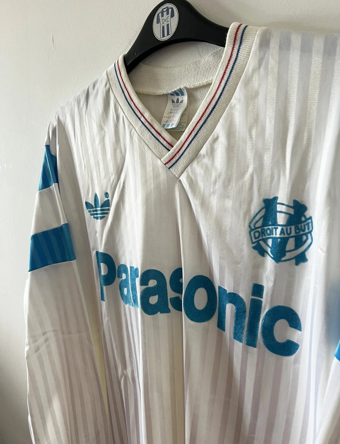 Maillot de foot vintage domicile blanc et bleu de l'om 1989/1991. On peut retrouver l'équipementier Adidas et le sponsor Panasonic. Il s'agit d'un maillot authentique d'époque.