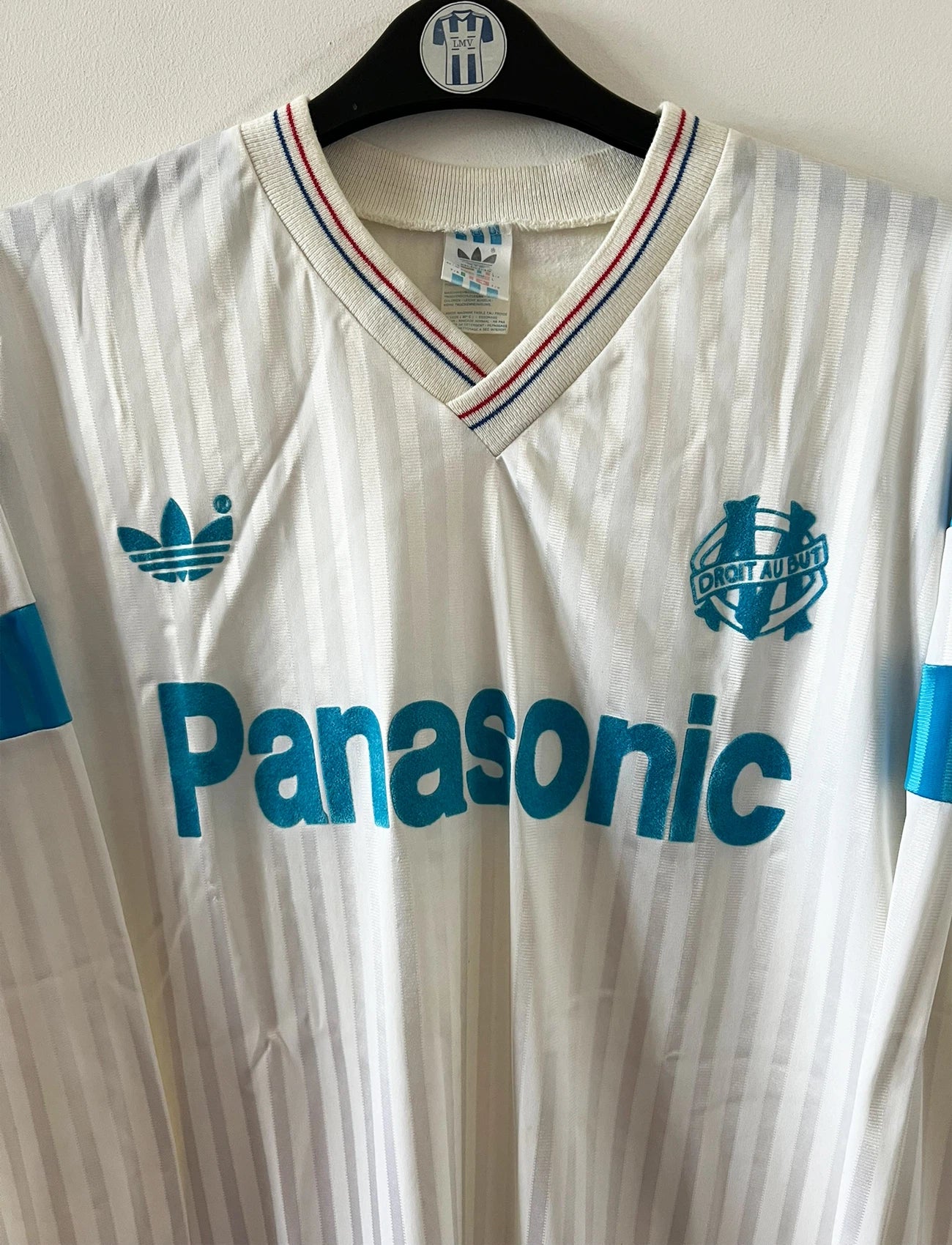 Maillot de foot vintage domicile blanc et bleu de l'om 1989/1991. On peut retrouver l'équipementier Adidas et le sponsor Panasonic. Il s'agit d'un maillot authentique d'époque.