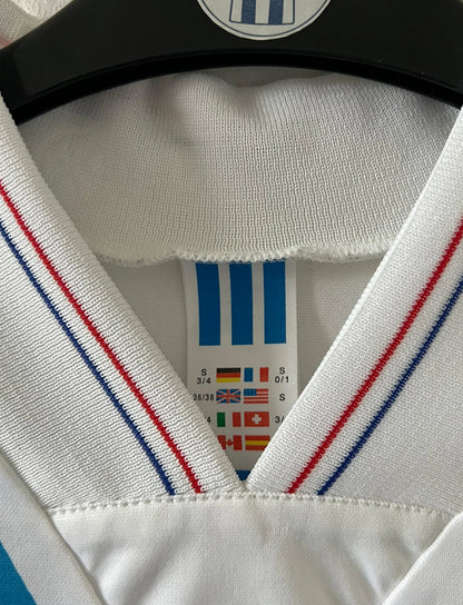 Maillot de foot vintage domicile blanc et bleu de la saison 1991/1992. On peut retrouver l'équipementier Adidas et le sponsor Panasonic. Il s'agit d'un maillot authentique d'époque.