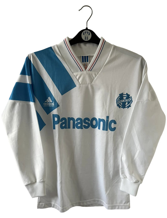Maillot de foot vintage domicile blanc et bleu de la saison 1991/1992. On peut retrouver l'équipementier Adidas et le sponsor Panasonic. Il s'agit d'un maillot authentique d'époque.