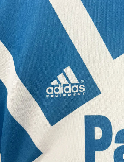 Maillot foot vintage domicile blanc et bleu de l'om de la saison 1991-1992. On peut retrouver l'équipementier adidas et le sponsor Panasonic. Il s'agit d'un maillot authentique d'époque.