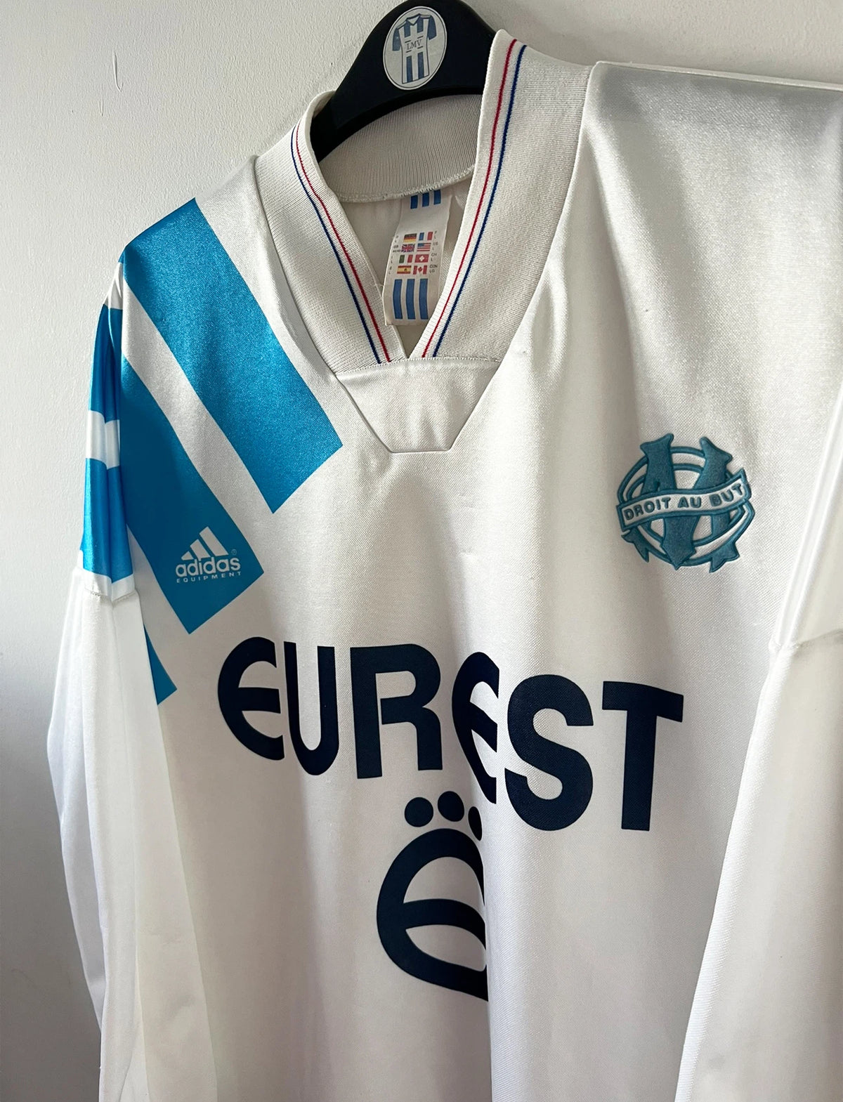 Maillot de foot vintage domicile blanc et bleu de l'OM 1992/1993. On peut retrouver l'équipementier Adidas et le sponsor Eurest. Il s'agit d'un maillot authentique d'époque.