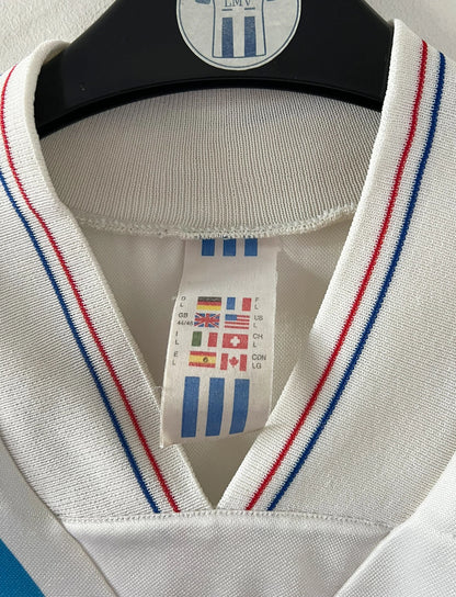 Maillot de foot vintage domicile blanc et bleu de l'OM 1992/1993. On peut retrouver l'équipementier Adidas et le sponsor Eurest. Il s'agit d'un maillot authentique d'époque.
