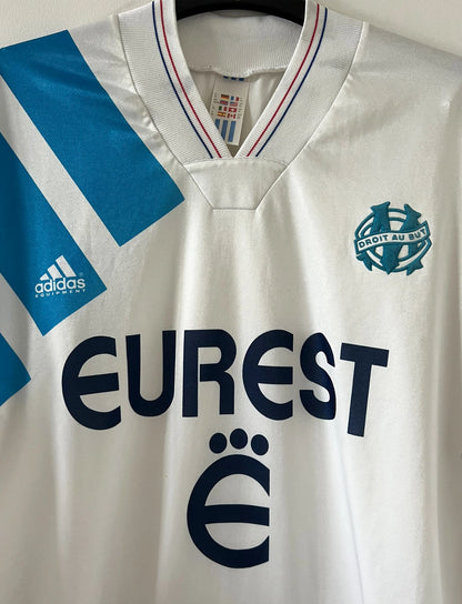 Maillot de foot vintage domicile OM 1992/1993. On peut retrouver l'équipementier Adidas et le sponsor Eurest. Il s'agit d'un maillot authentique d'époque.
