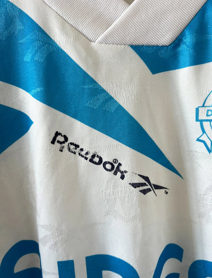 Maillot de foot vintage domicile blanc et bleu de l'OM 1994/1995. On peut retrouver l'équipementier Reebok et le sponsor Eurest. Il s'agit d'un maillot authentique d'époque.