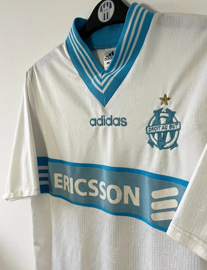 Maillot de foot vintage domicile blanc et bleu de l'OM saison 1997/1998. On peut retrouver l'équipementier Adidas et le sponsor Ericsson. Il s'agit d'un maillot authentique d'époque.