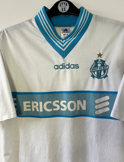 Maillot de foot vintage domicile blanc et bleu de l'OM saison 1997/1998. On peut retrouver l'équipementier Adidas et le sponsor Ericsson. Il s'agit d'un maillot authentique d'époque.