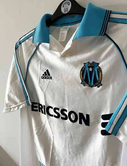 Maillot de foot vintage domicile de l'OM de la saison 1998/1999. On peut retrouver l'équipementier Adidas et le sponsor Ericsson. Le maillot est floqué du numéro 7 Robert Pirès. Il s'agit d'un maillot authentique d'époque.
