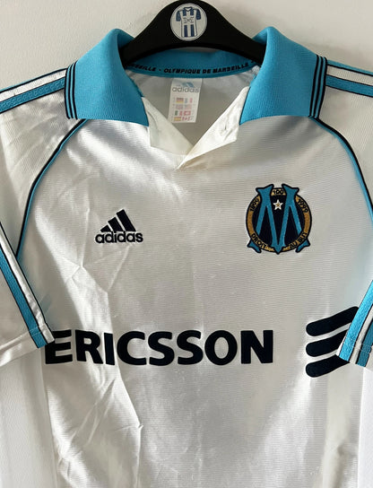 Maillot de foot vintage domicile de l'OM de la saison 1998/1999. On peut retrouver l'équipementier Adidas et le sponsor Ericsson. Le maillot est floqué du numéro 7 Robert Pirès. Il s'agit d'un maillot authentique d'époque.