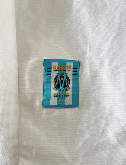 Maillot de foot vintage domicile blanc de l'OM 1998/1999. On peut retrouver l'équipementier Adidas et le sponsor Ericsson. Il s'agit d'un maillot authentique d'époque.