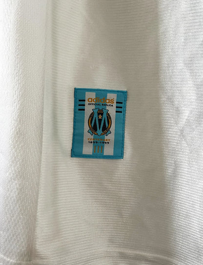 Maillot de foot vintage domicile OM 1998/1999. On peut retrouver l'équipementier Adidas et le sponsor Ericsson. Il s'agit d'un maillot authentique d'époque.