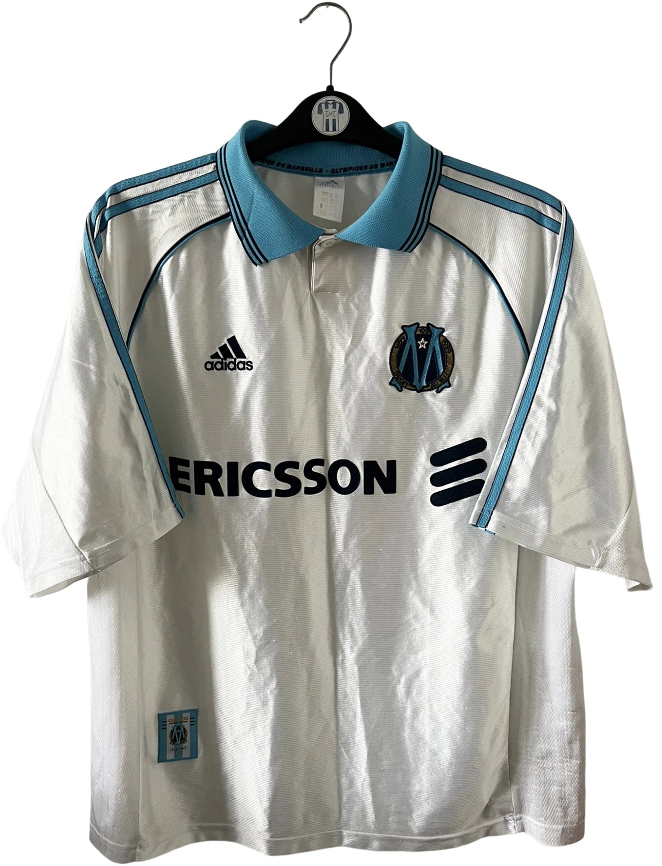 Maillot de foot vintage domicile OM 1998/1999. On peut retrouver l'équipementier Adidas et le sponsor Ericsson. Il s'agit d'un maillot authentique d'époque.