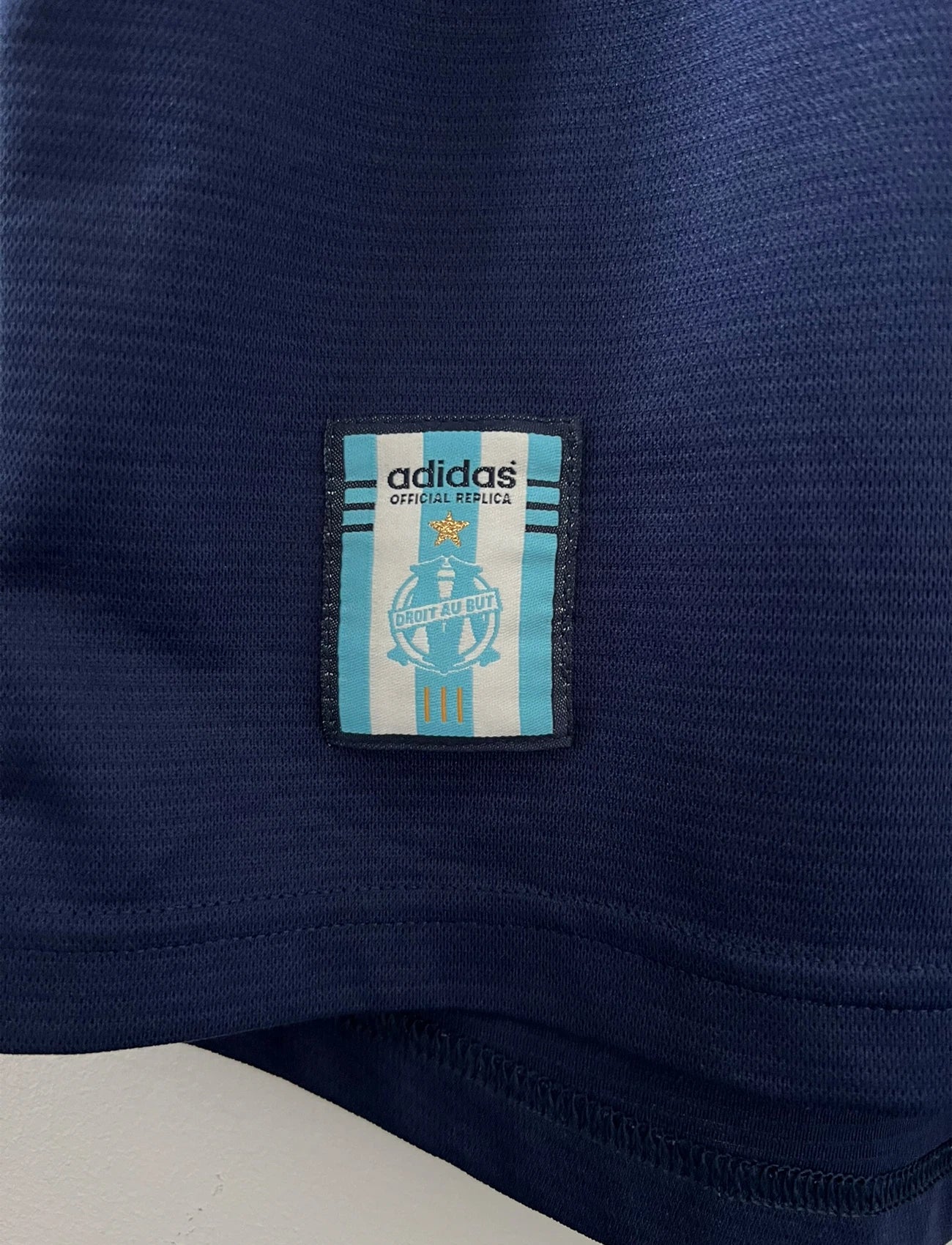 Maillot de foot vintage OM 1999/2000 extérieur bleu. On peut retrouver l'équipementier Adidas et le sponsor Ericsson. Il s'agit d'un maillot authentique d'époque.