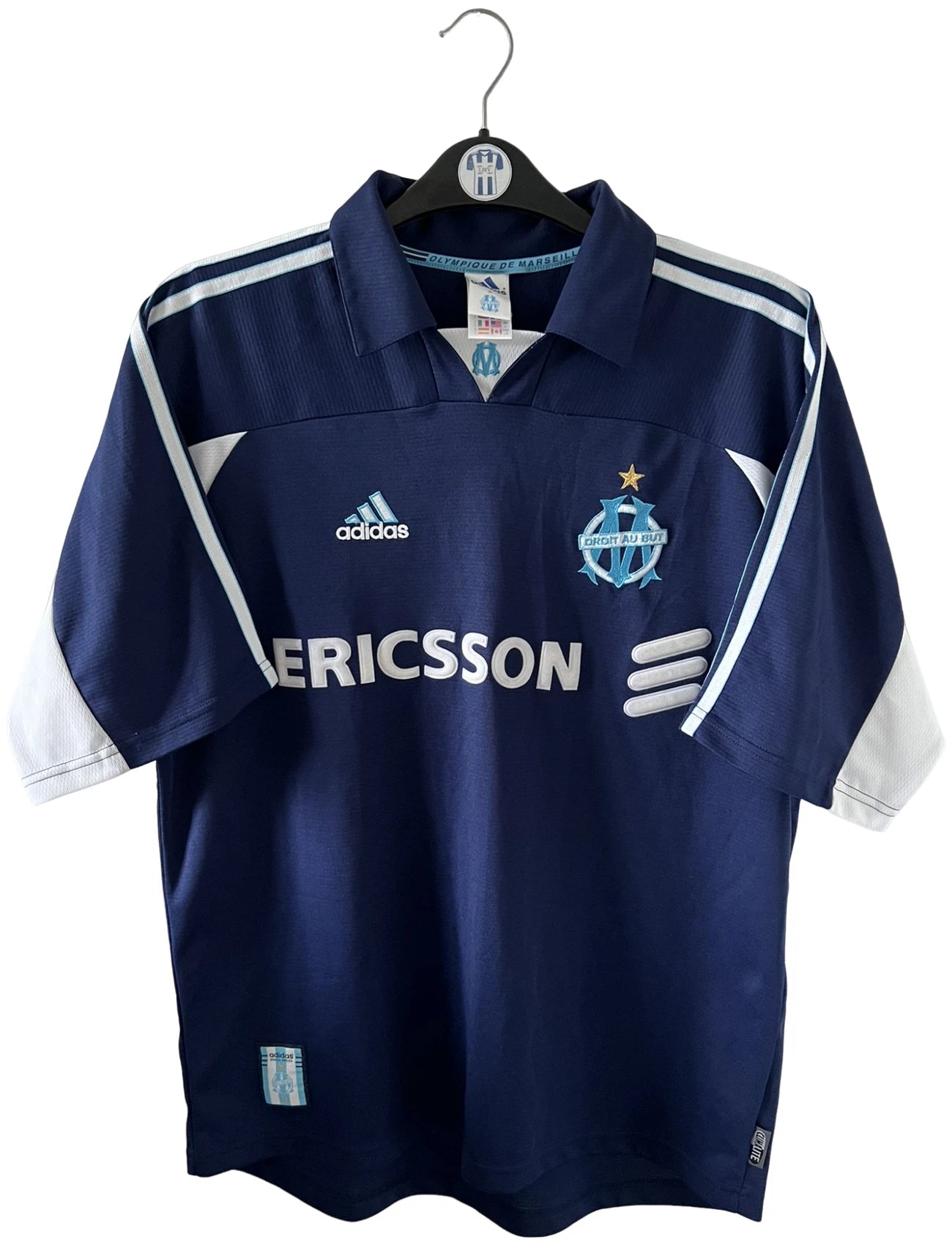 Maillot de foot vintage OM 1999/2000 extérieur bleu. On peut retrouver l'équipementier Adidas et le sponsor Ericsson. Il s'agit d'un maillot authentique d'époque.