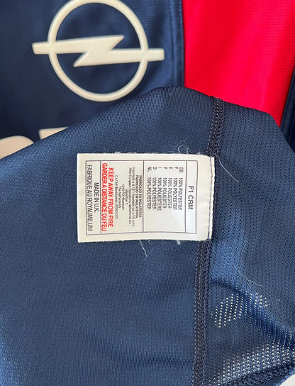 Maillot de foot vintage domicile bleu et rouge du PSG 2001/2002. On peut retrouver l'équipementier Nike et le sponsor OPEL. Il s'agit d'un maillot authentique d'époque.