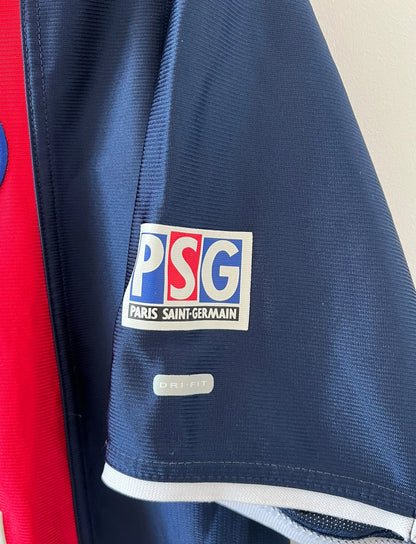 Maillot de foot vintage domicile bleu et rouge du PSG 2001/2002. On peut retrouver l'équipementier Nike et le sponsor OPEL. Il s'agit d'un maillot authentique d'époque.
