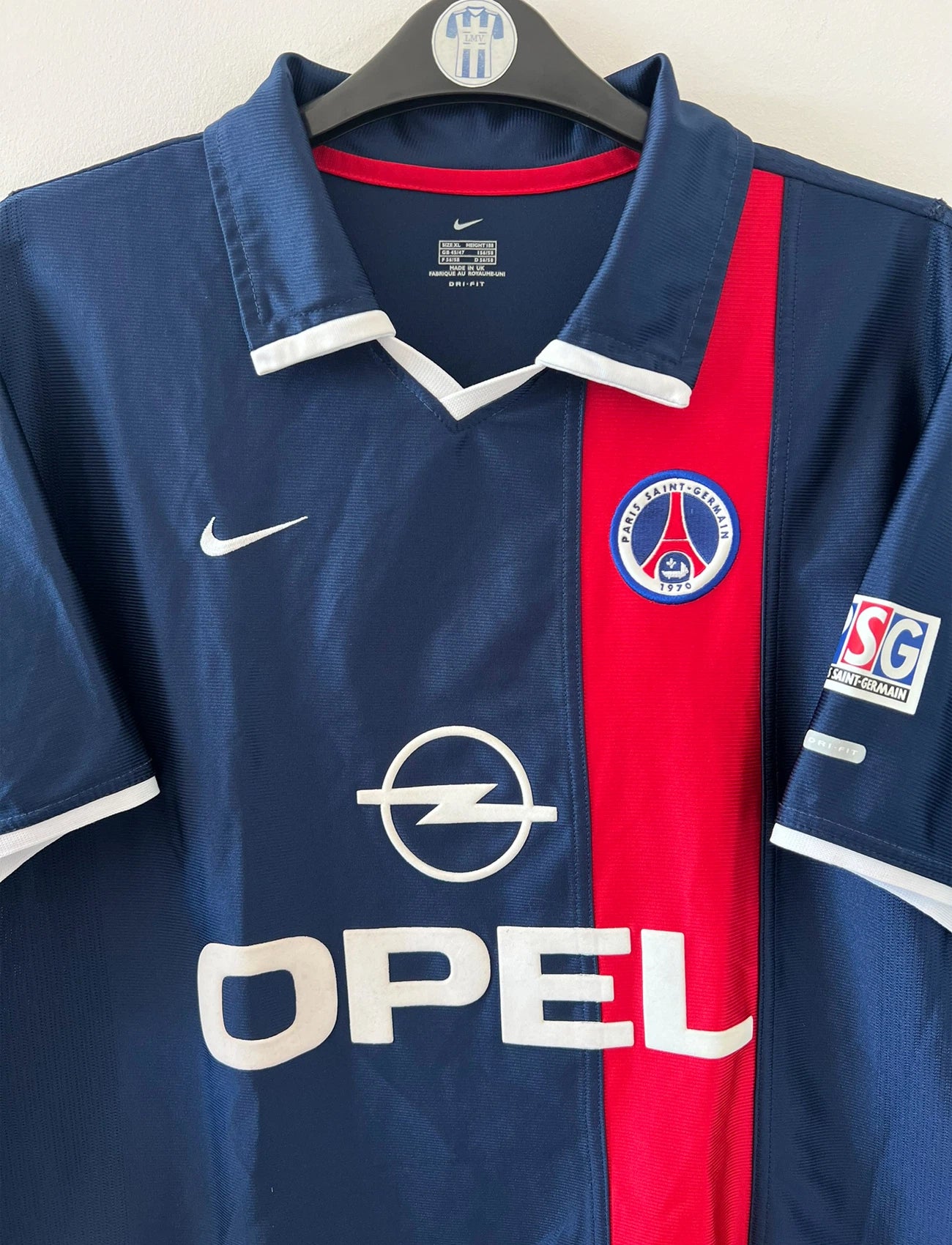 Maillot de foot vintage domicile bleu et rouge du PSG 2001/2002. On peut retrouver l'équipementier Nike et le sponsor OPEL. Il s'agit d'un maillot authentique d'époque.