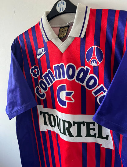 Maillot de foot vintage domicile rouge et bleu du PSG 1993/1994. On peut retrouver l'équipementier Nike et le sponsor Tourtel et Commodore. Il s'agit d'un maillot authentique d'époque.