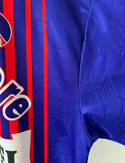 Maillot vintage domicile rouge et bleu du PSG de la saison 1993/1994. On peut retrouver l'équipementier nike, le sponsor commodore et le sponsor tourtel. Il s'agit d'un maillot authentique d'époque.