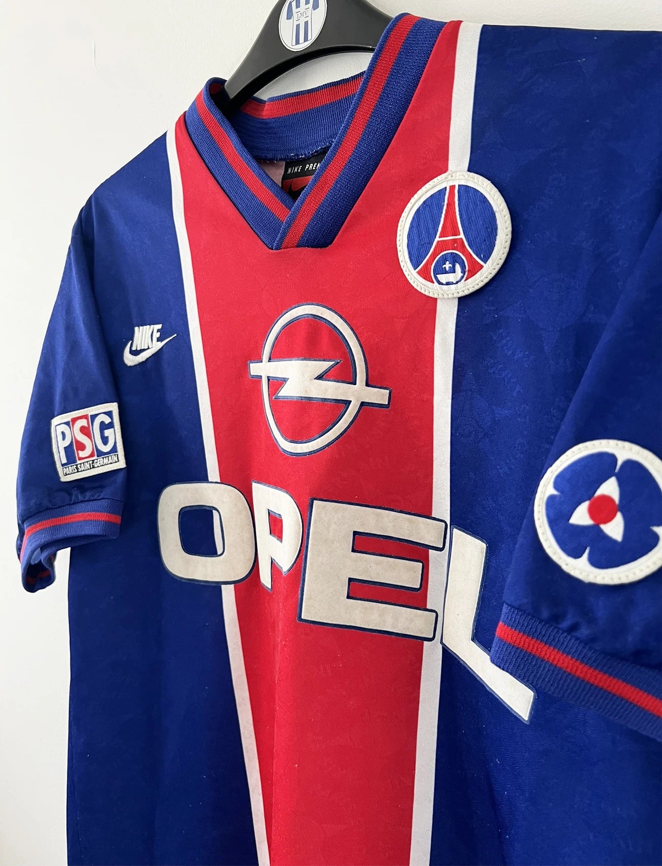 Maillot de foot vintage domicile bleu et rouge du PSG de la saison 1995/1996. On peut retrouver l'équipementier Nike et le sponsor Opel. Il s'agit d'un maillot authentique d'époque.