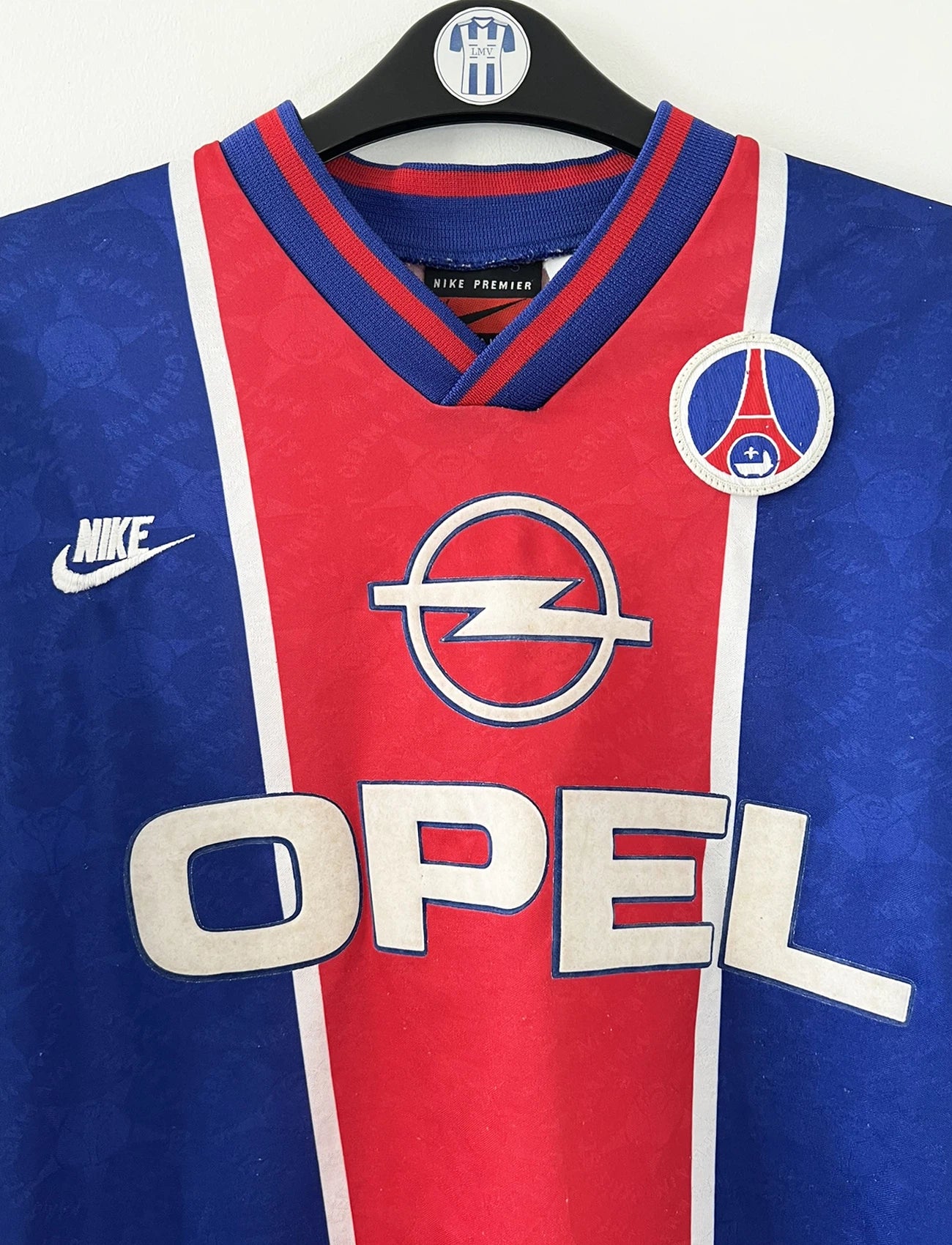 Maillot de foot vintage domicile bleu et rouge du PSG de la saison 1995/1996. On peut retrouver l'équipementier Nike et le sponsor Opel. Il s'agit d'un maillot authentique d'époque.