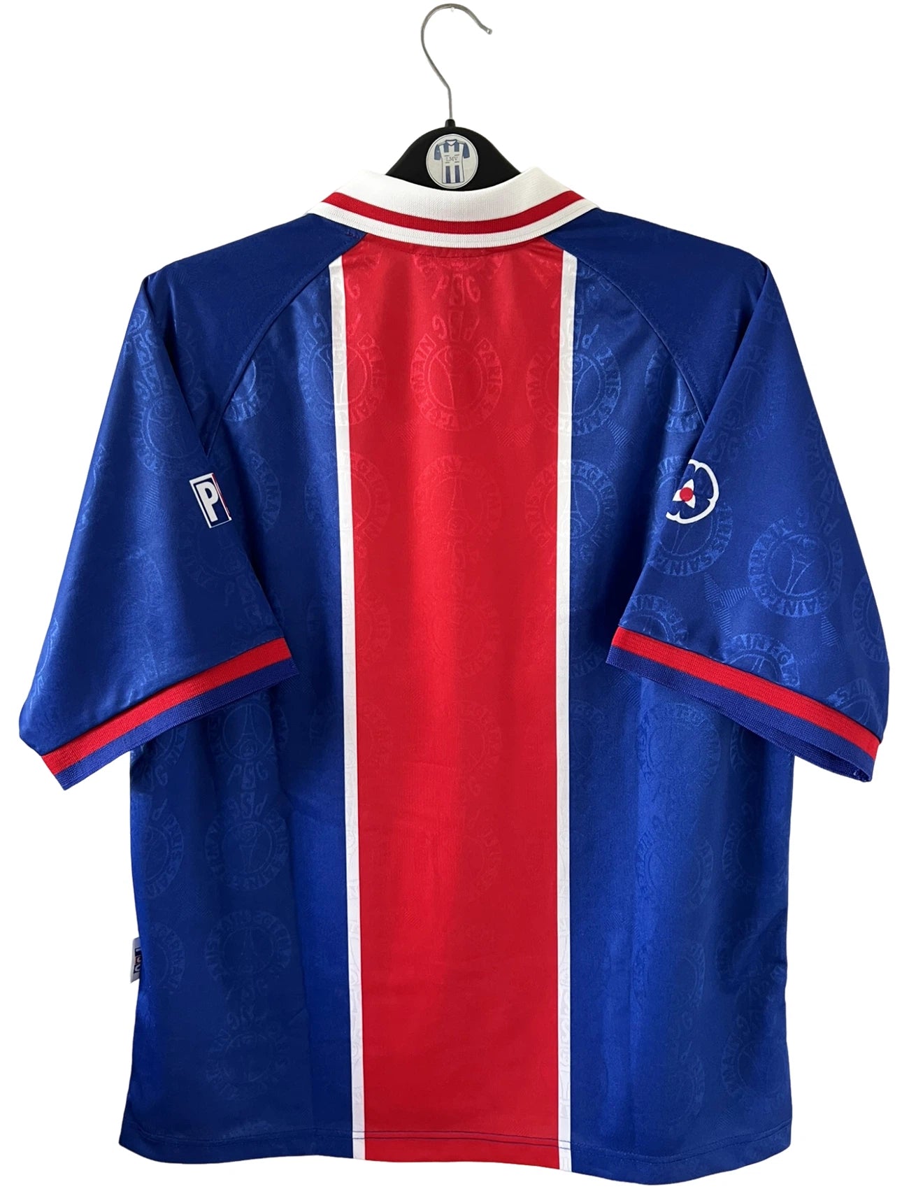 Maillot de foot vintage domicile rouge et bleu du PSG de la saison 1996/1997. On peut retrouver la fameuse bande hechter avec l'équipementier Nike et le sponsor Opel. Il s'agit d'un maillot authentique d'époque.