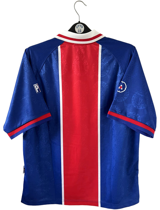 Maillot de foot vintage domicile rouge et bleu du PSG de la saison 1996/1997. On peut retrouver la fameuse bande hechter avec l'équipementier Nike et le sponsor Opel. Il s'agit d'un maillot authentique d'époque.